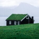 Photo by Tomáš Malík Charming black wooden house with a grass roof